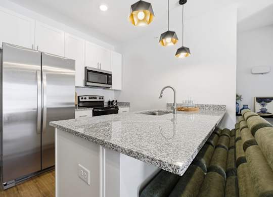 A kitchen with a granite countertop and stainless steel appliances.