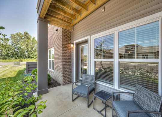 A patio with a couch, chair and table.