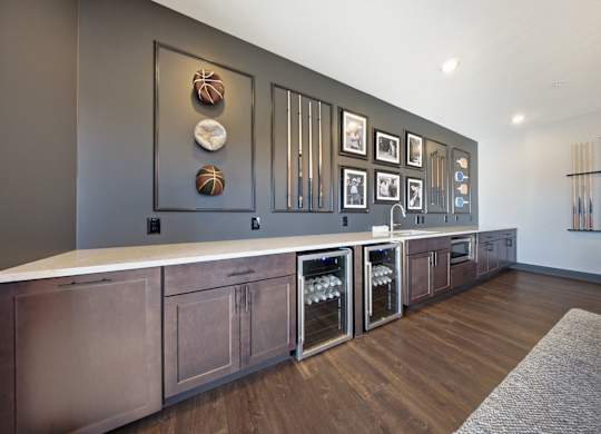 A kitchen with a long counter and a row of wine glasses on the wall.
