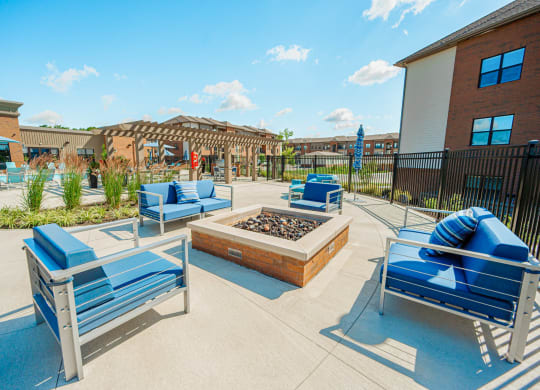 a patio with blue chairs and a fire pit