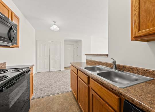 A kitchen with brown cabinets and a black stove top oven.
