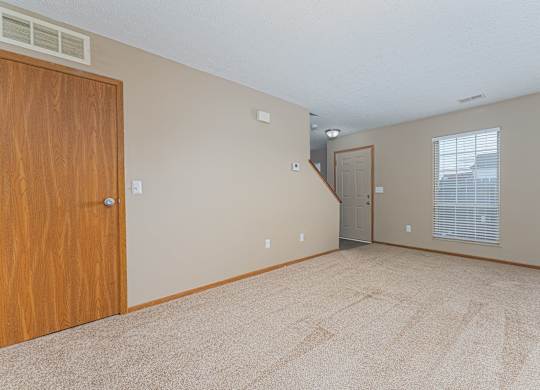 A room with a carpeted floor and a wooden door.