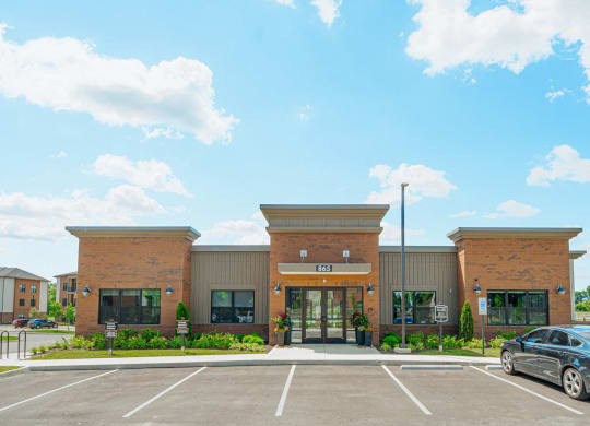 the front of a brick building with a car parked in a parking lot