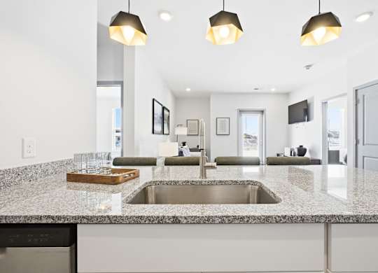 A modern kitchen with a granite countertop and a double sink.