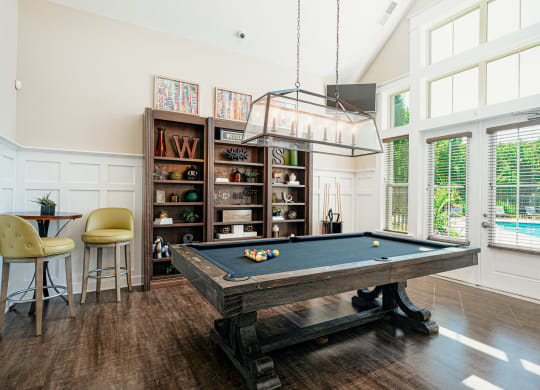 a pool table in a living room with a light hanging over it