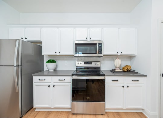 a white kitchen with stainless steel appliances and white cabinets