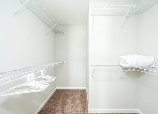 a walk in closet with a mirrored closet door and a shelf with towels