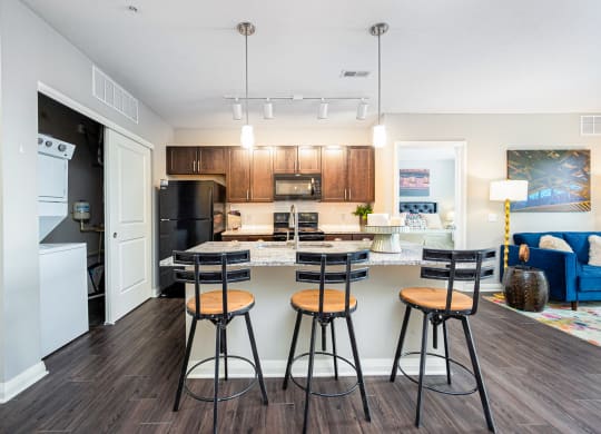 a kitchen with a bar and stools and a living room