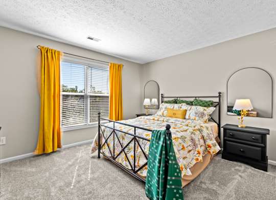 A bedroom with a bed, dresser, and window with yellow curtains.