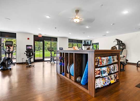 A gym with a variety of equipment and a wooden shelf with colorful items.
