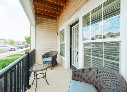 a porch with two chairs and a table and a large window