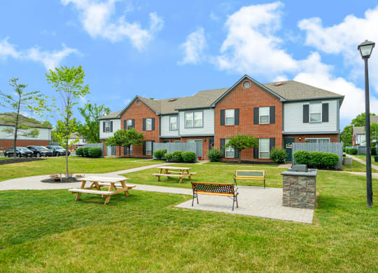 a park with picnic tables in front of a house