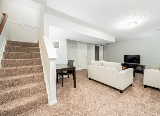 a living room with a staircase and a couch and a tv