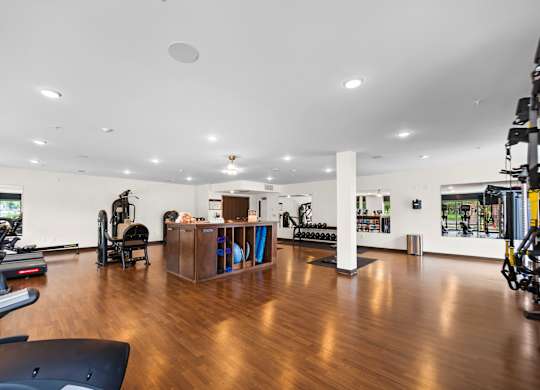 A gym with a variety of equipment including treadmills, weights, and exercise machines.