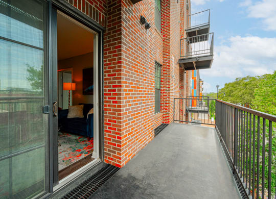 a balcony with a glass door and a brick building