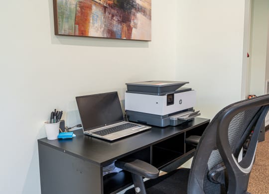 an office desk with a laptop computer and a printer on it