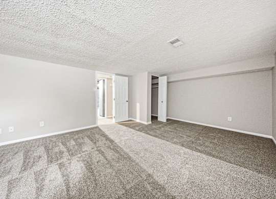 A spacious room with a carpeted floor and white walls.