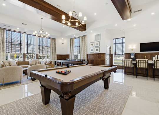 A large billiard table is in the middle of a spacious room with a pool table and a couch.