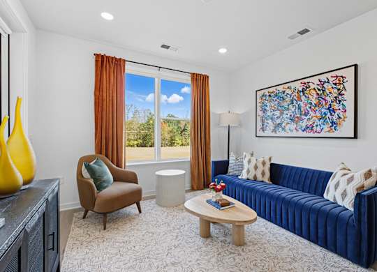 A living room with a blue couch, a brown chair, a coffee table, and a painting on the wall.