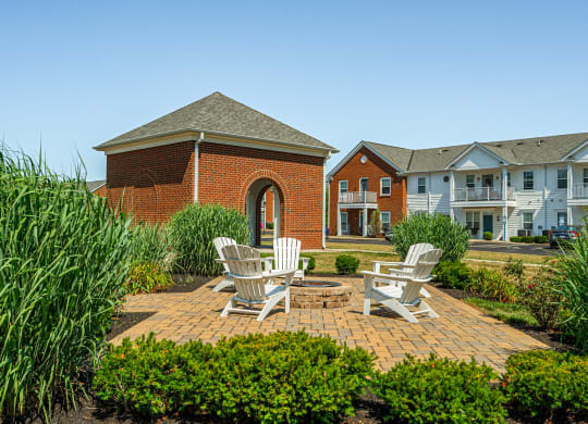 a brick patio with two chairs and a fire pit in front of a brick building
