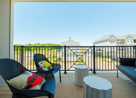 a balcony with chairs and tables and a view of a yard and houses