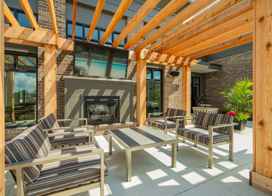 a covered patio with chairs and a fireplace