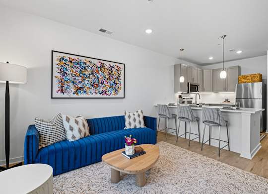 A blue couch with a white and grey pillow sits in a living room with a coffee table in front of it.