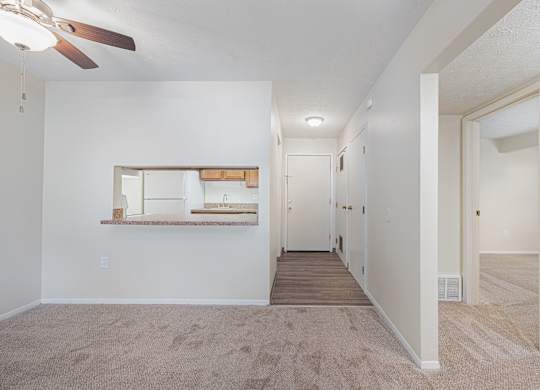 an empty living room and hallway with a ceiling fan