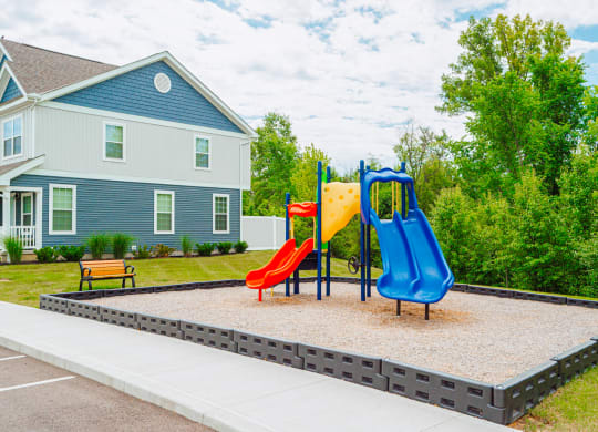 a playground with two slides in front of a house