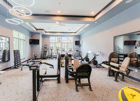 A spacious gym with various exercise equipment and mirrors.