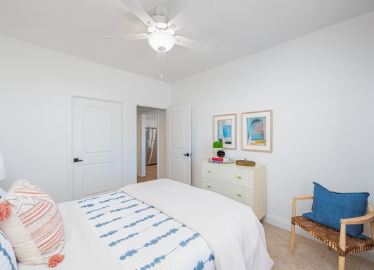a white bedroom with a bed and a ceiling fan