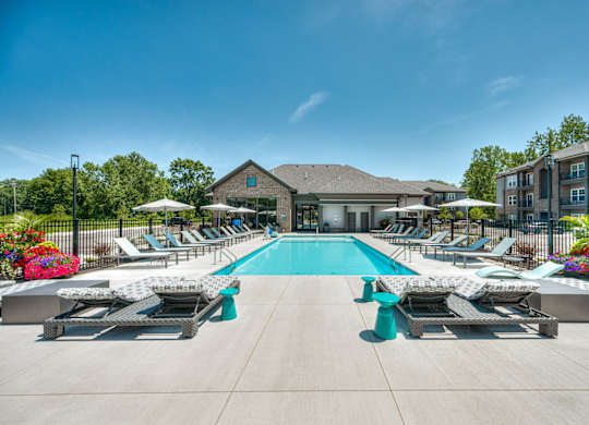 A large swimming pool surrounded by lounge chairs and umbrellas.