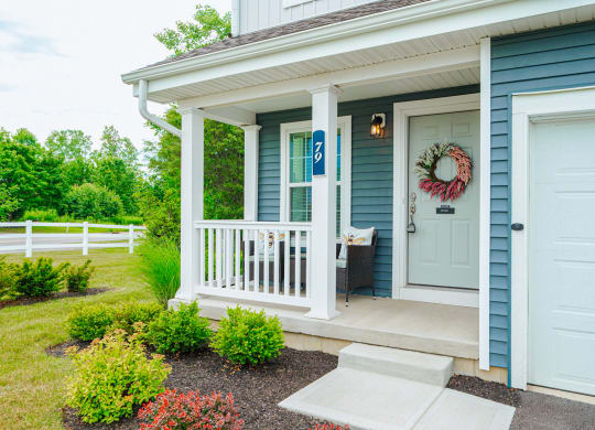 the front porch of a blue house with a white door