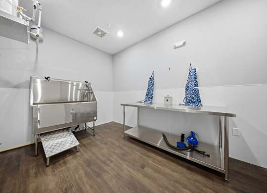 A clean, empty room with a stainless steel sink and a wooden floor.
