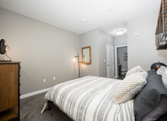 a bedroom with a bed and a dresser and a bathroom