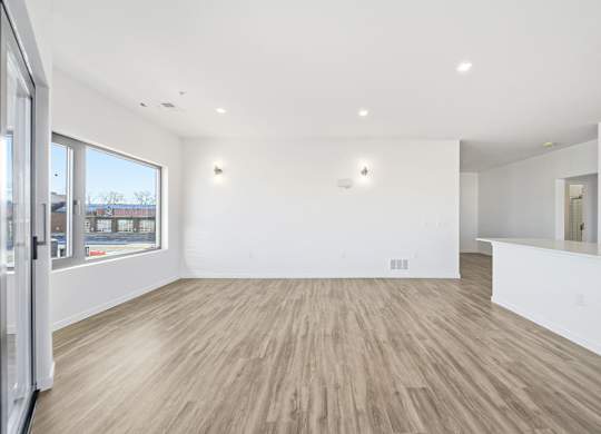 A spacious room with wooden flooring and white walls.