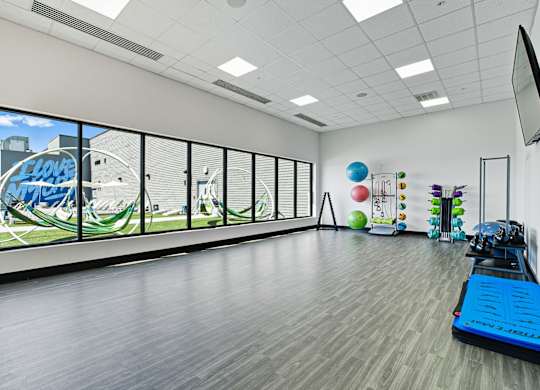 A gym with a treadmill, exercise balls, and a television showing a golf course.