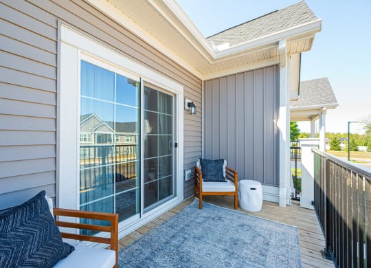 a covered porch with two chairs and sliding glass doors