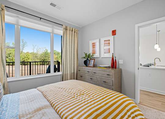 A bedroom with a bed, dresser, and window.