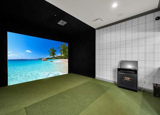 A room with a large screen displaying a beach scene.