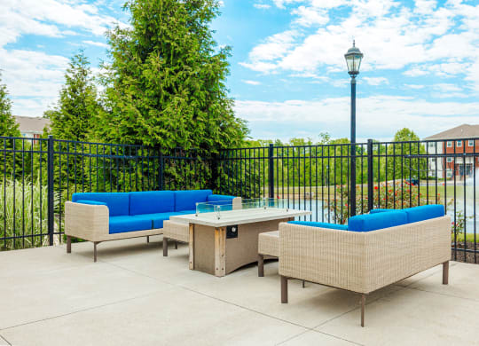 a patio with couches and a table in front of a fence