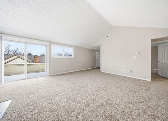 Empty room with carpeted floor and sliding glass doors.