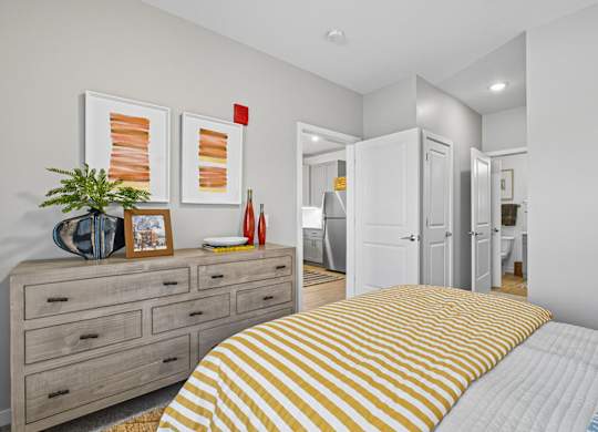 A bedroom with a bed, dresser, and two framed pictures on the wall.