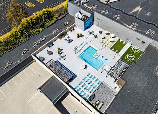 A rooftop pool and patio area with a table and chairs.