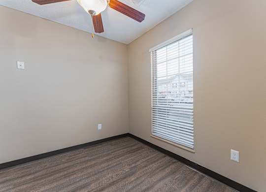 A room with a ceiling fan and a window with blinds