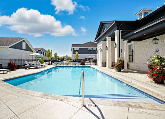 A swimming pool surrounded by a concrete patio and a building in the background.