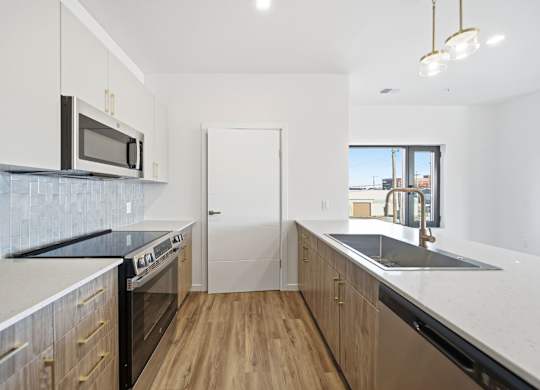 A kitchen with wooden floors and a black counter top.