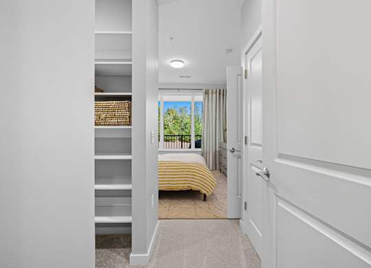 A white hallway with a bedroom at the end.