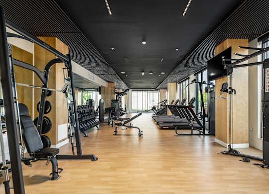 A gym with a variety of equipment including treadmills, weights, and exercise machines.
