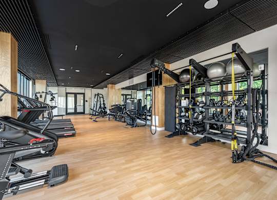 A gym with a variety of equipment including treadmills, weights, and exercise machines.